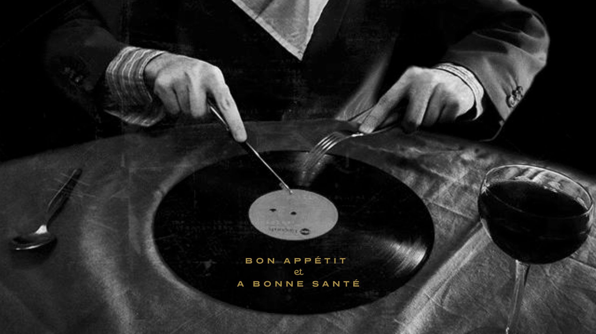 A diner in a suit cutting into a vinyl record with a knife and fork beside a glass of wine, captioned “Bon appétit et à bonne santé.”